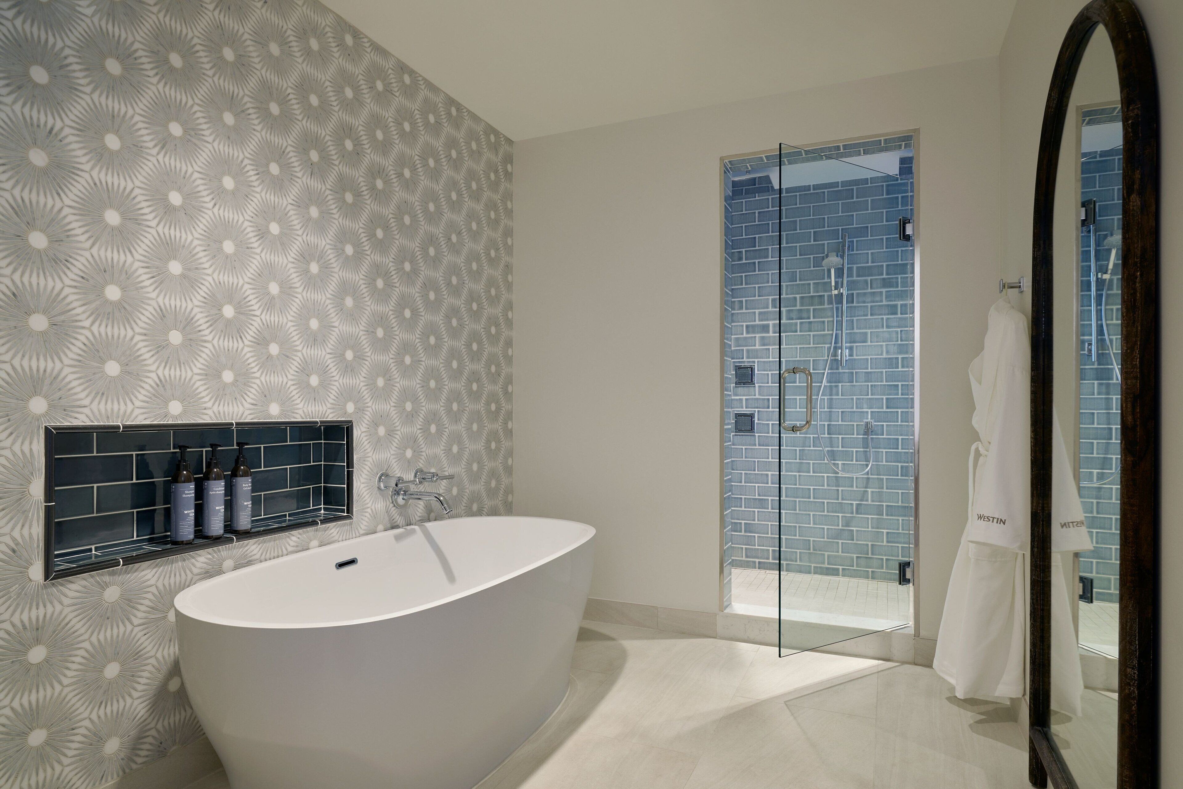 A modern bathroom with a freestanding bathtub, a glass shower enclosure, and a mirror with a dark frame.