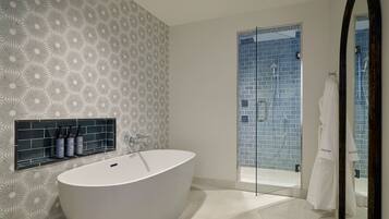 A modern bathroom with a freestanding bathtub, a glass shower enclosure, and a mirror with a dark frame.