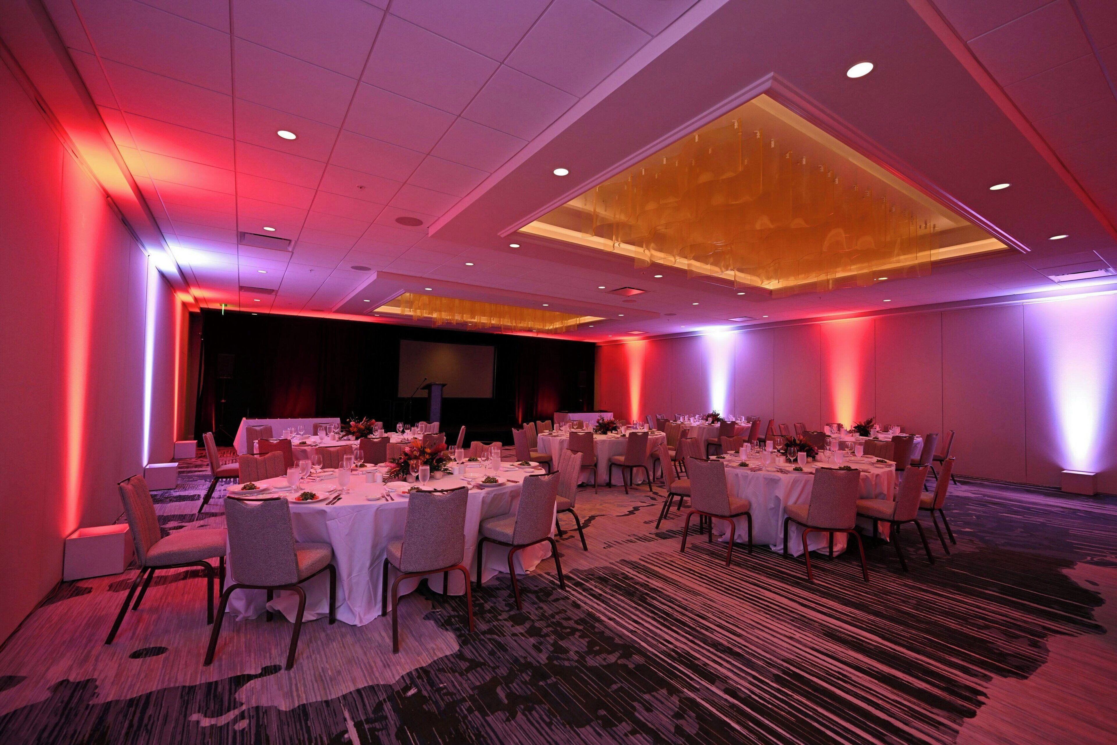 A conference room with round tables, chairs, and a stage.