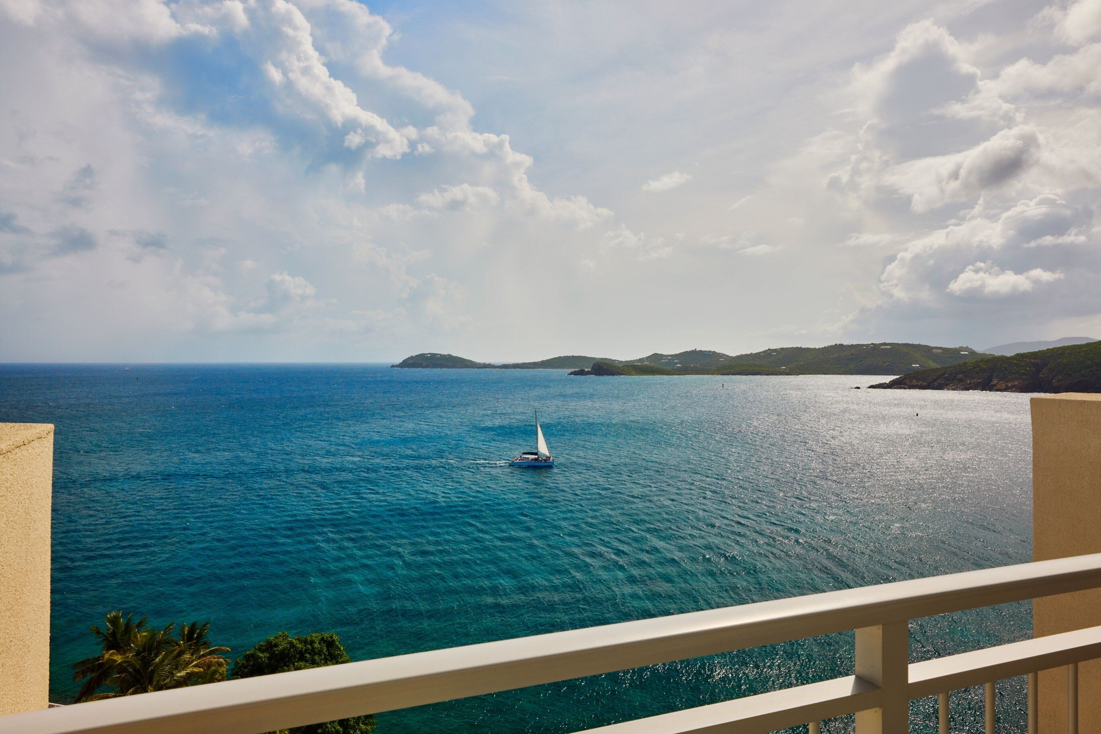 A balcony with a view of the sea and distant hills.