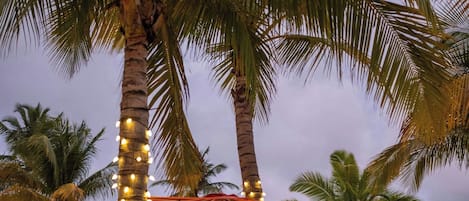 A beach area with palm trees, a red umbrella, and a sign welcoming visitors to Life on the Sea.
