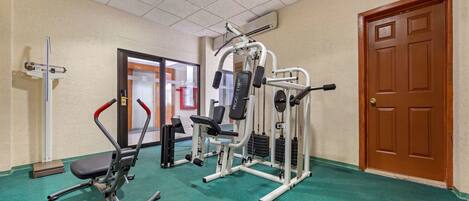 A gym with exercise equipment, a door, and a carpeted floor.