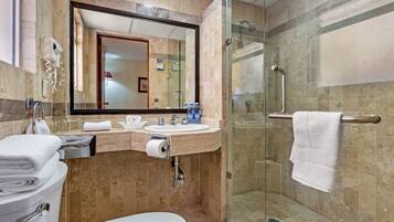 Un baño moderno con ducha acristalada, lavamanos con espejo y un inodoro.