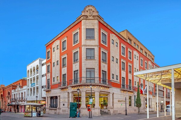 A corner building with a prominent entrance, multiple windows, and a balcony.