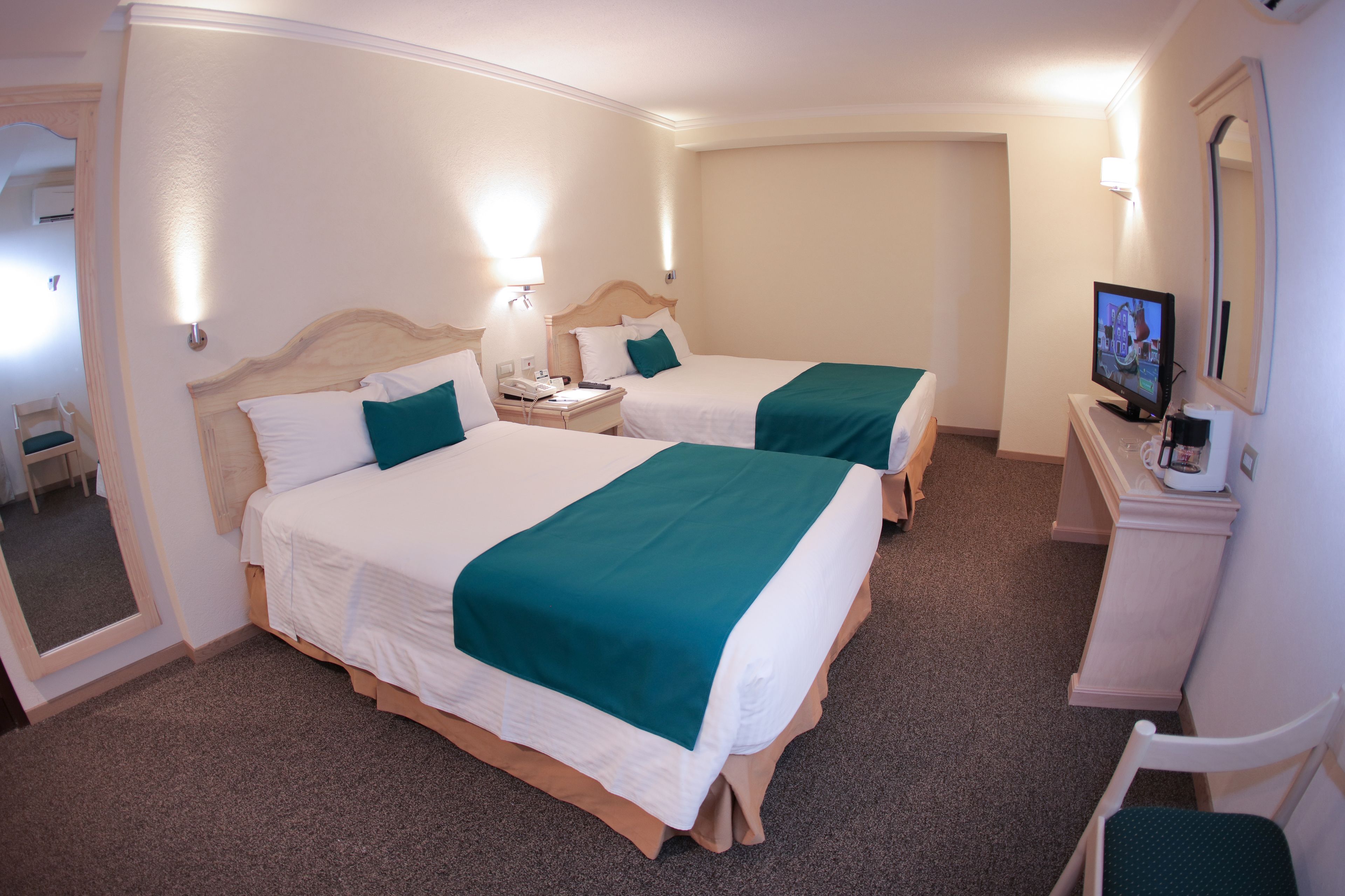 A hotel room with two beds, a desk with a computer, and a chair.