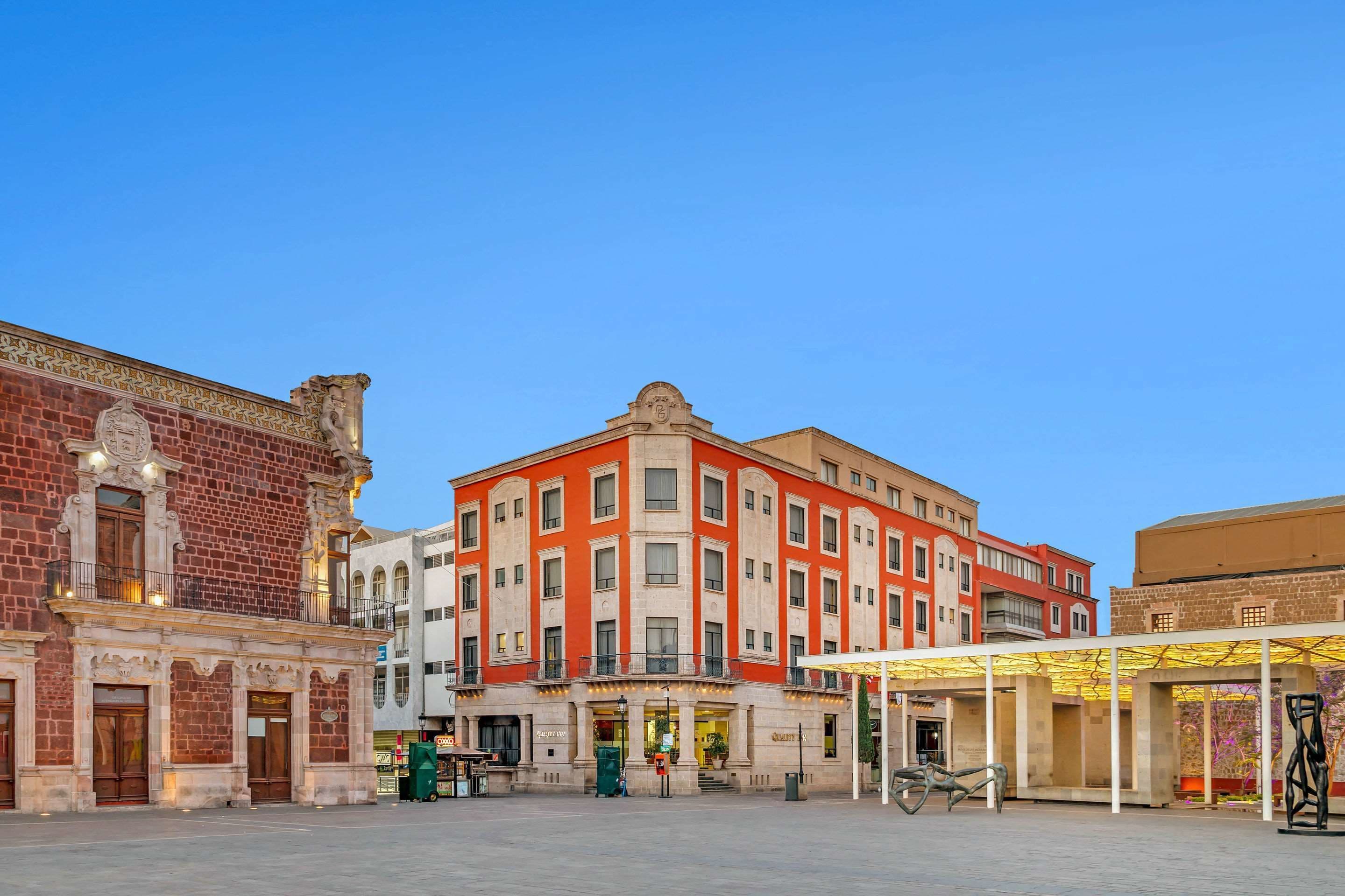 En historisk byggnad med en röd fasad, stora fönster och en central entré.