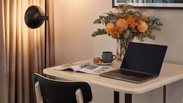 A laptop on a table with a magazine, a cup, and a pastry.