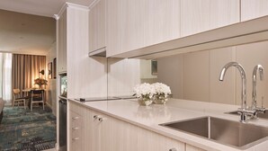 A modern kitchen with a large sink, light wood cabinetry, and a vase of white flowers on the countertop. - Rydges Darling Square Apartment Hotel (Sydney)