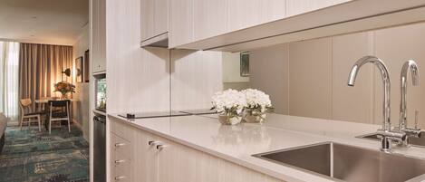A modern kitchen with a large sink, light wood cabinetry, and a vase of white flowers on the countertop.