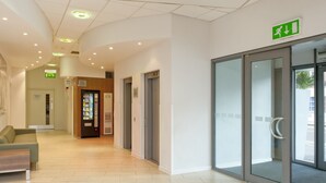 A modern hotel lobby with a reception desk, a vending machine, and an elevator. - Holiday Inn Express London City by IHG (London)