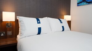 A hotel room with a neatly made bed, two bedside lamps, and a wooden nightstand with a lamp and a power outlet. - Holiday Inn Express London City by IHG (London)