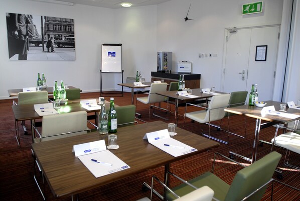 A conference room with multiple tables, chairs, and a whiteboard.
