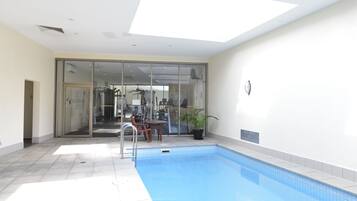 Relax by the rectangular pool surrounded by a tiled floor and enjoy the adjacent seating area with a table and chairs.