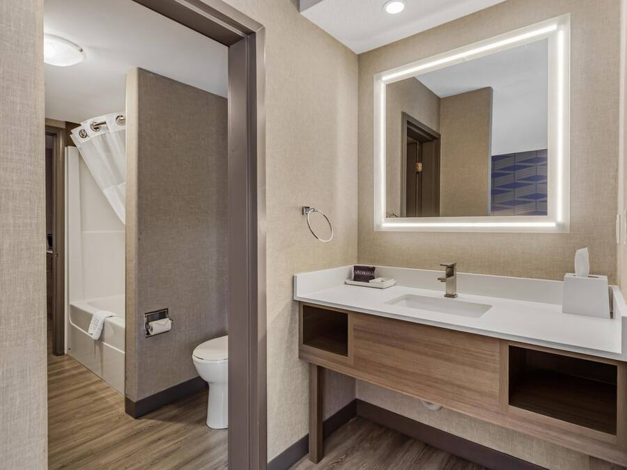 A modern bathroom with a wooden vanity, a large mirror, and a shower area.