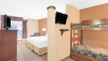 A hotel room with a bed, a desk, a television mounted on the wall, and a bunk bed.