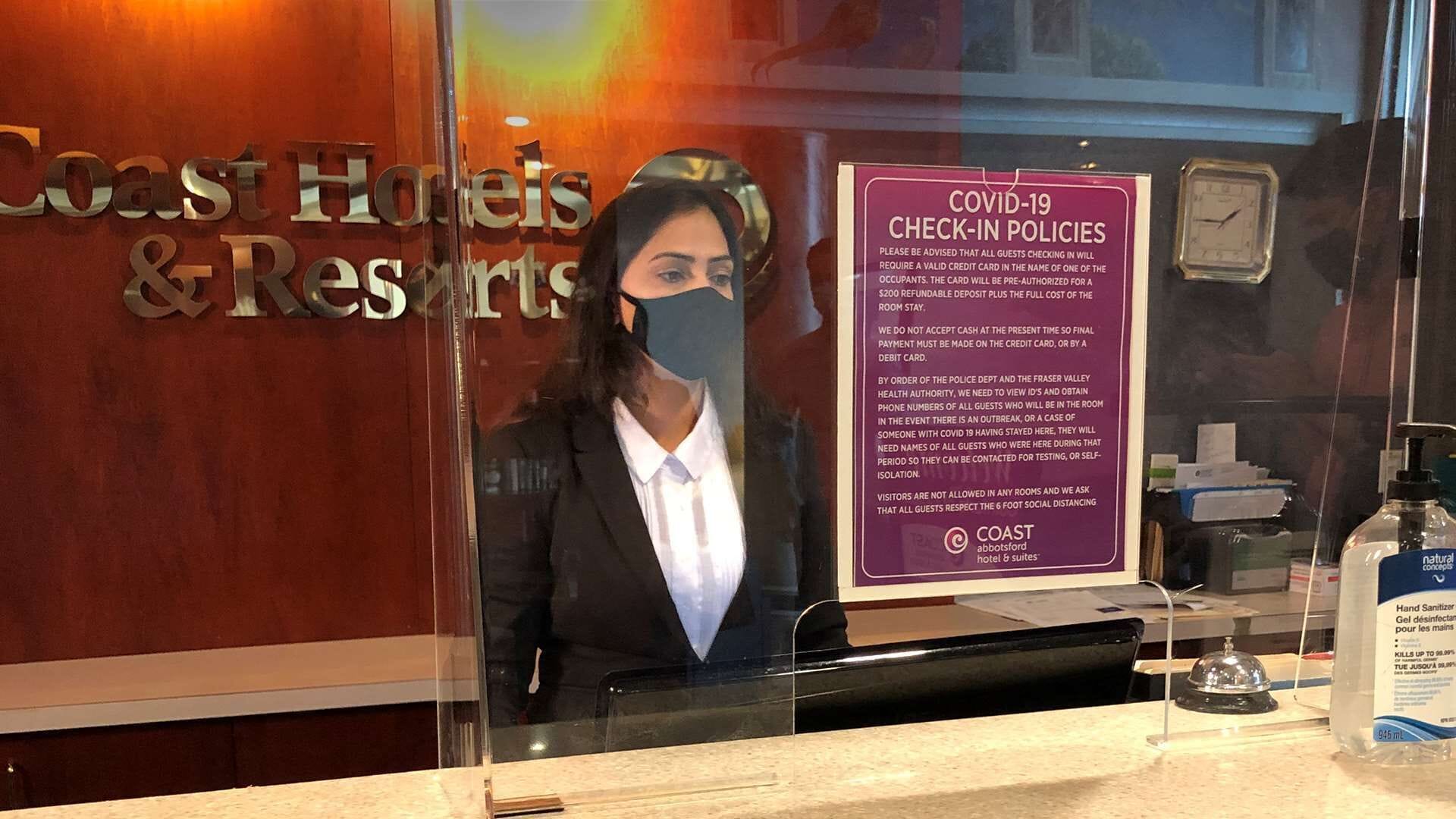 Una recepción con un cartel que detalla las políticas de registro por COVID-19.