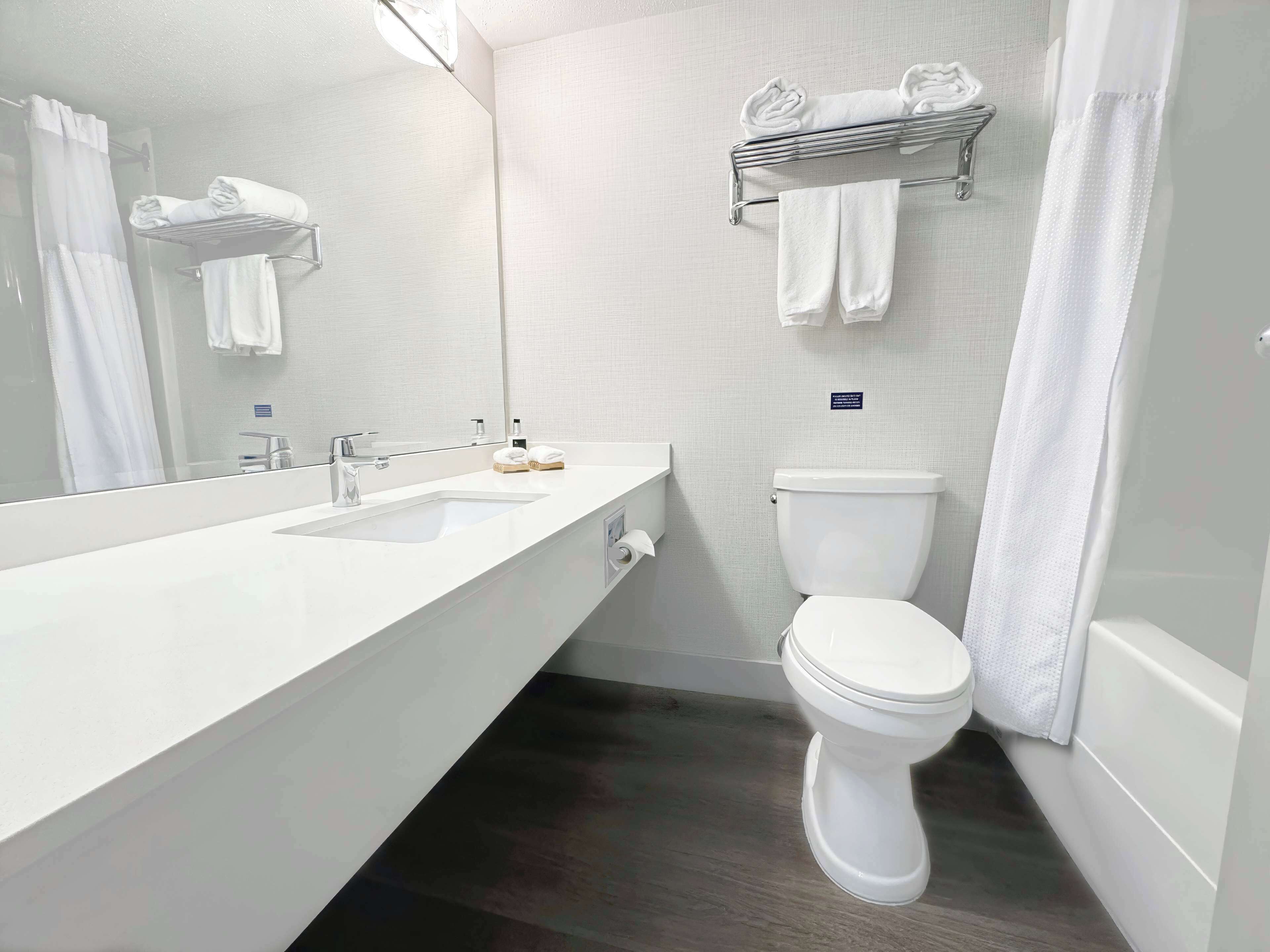 Un baño moderno con lavamanos doble, inodoro, toallero y espejo.