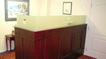 A reception desk with a framed certificate on the wall and a framed picture above it.