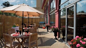 An outdoor patio with wooden tables and chairs, large umbrellas, and potted plants. - Residence Inn by Marriott London Ontario (London)