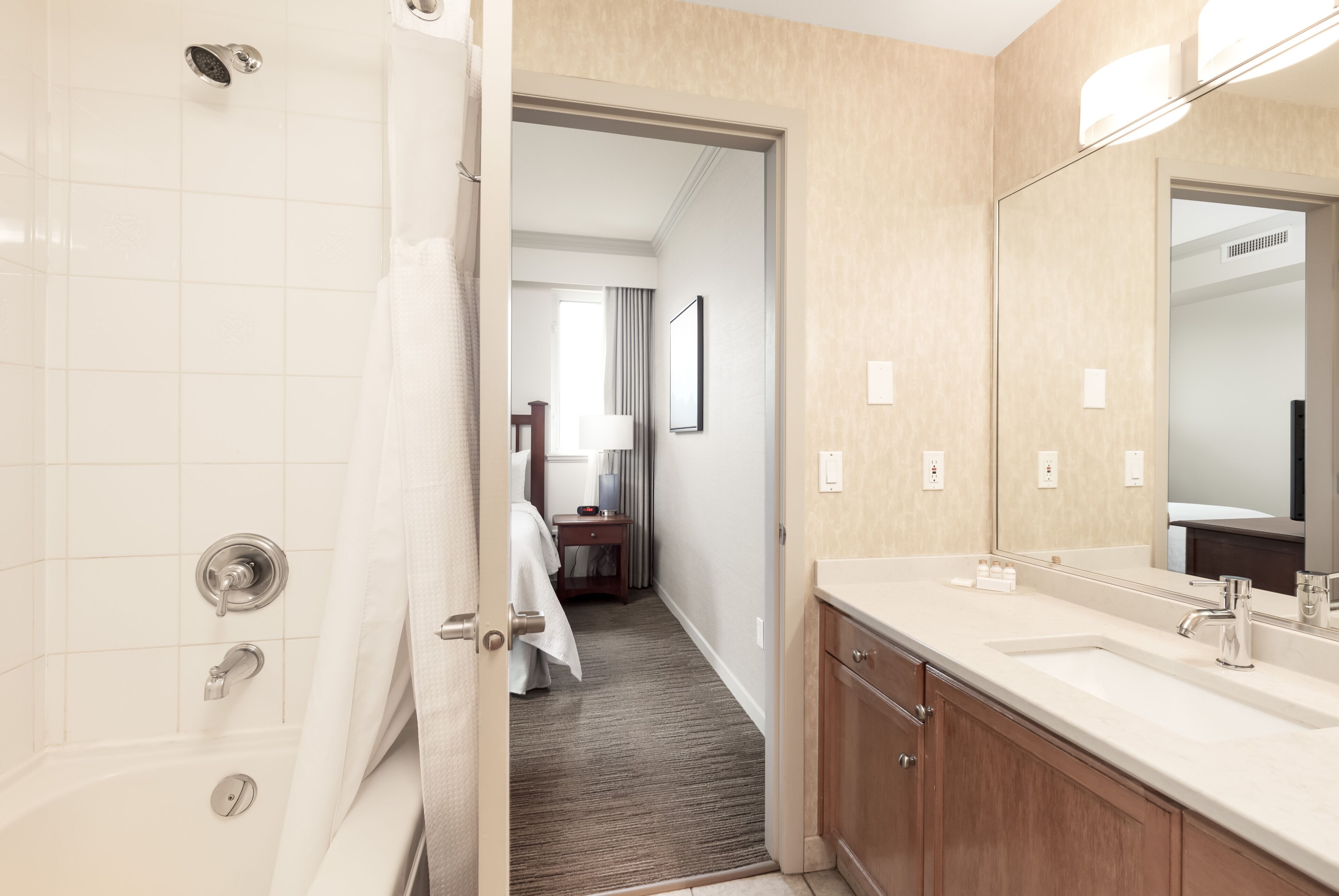 A hotel bathroom with a bathtub, a sink, and a mirror.