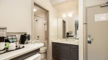 A modern bathroom with a coffee station, a large mirror, and a door with a sign.