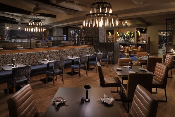 A restaurant with a bar area, booths, and high-end lighting fixtures.