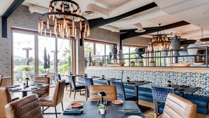 Un restaurante moderno con asientos de cuero, una zona de bar con vistas y una variedad de plantas y objetos decorativos.