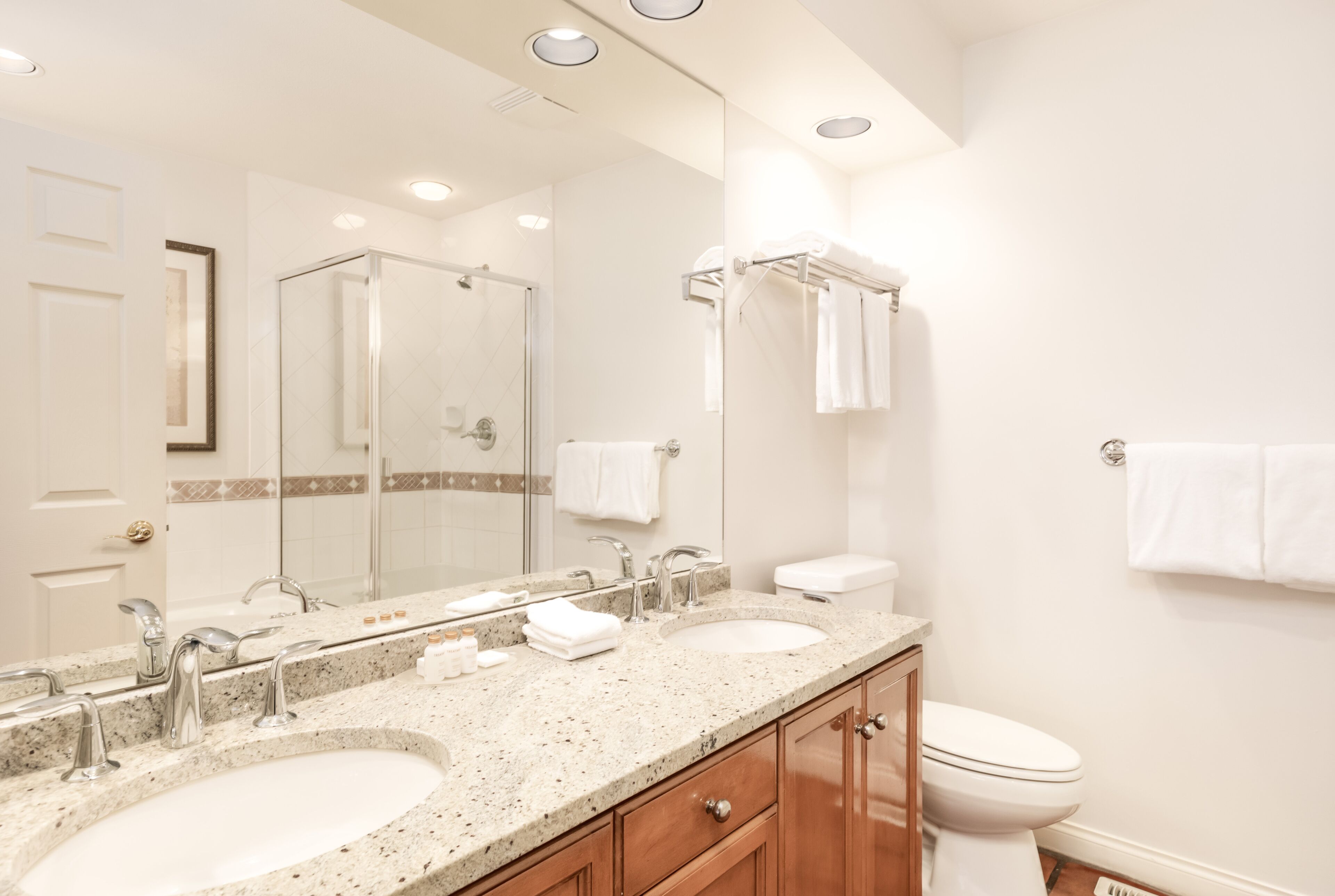 A modern bathroom with two sinks, a large mirror, and a shower.