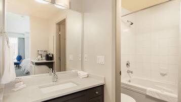 A modern bathroom with a large mirror, two sinks, a toilet, and a bathtub.