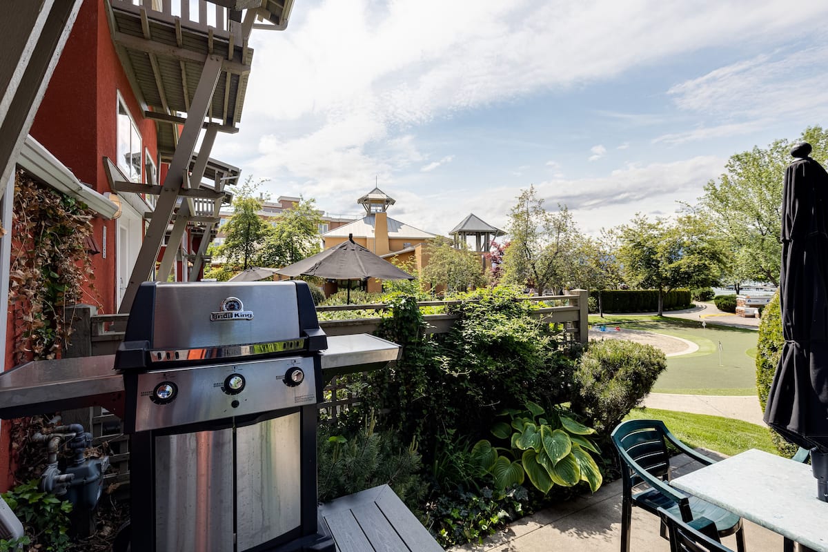 Un patio con parrilla, mobiliario exterior y vistas de los edificios circundantes.