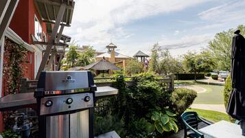 A patio area with a grill, outdoor seating, and a view of the surrounding buildings.