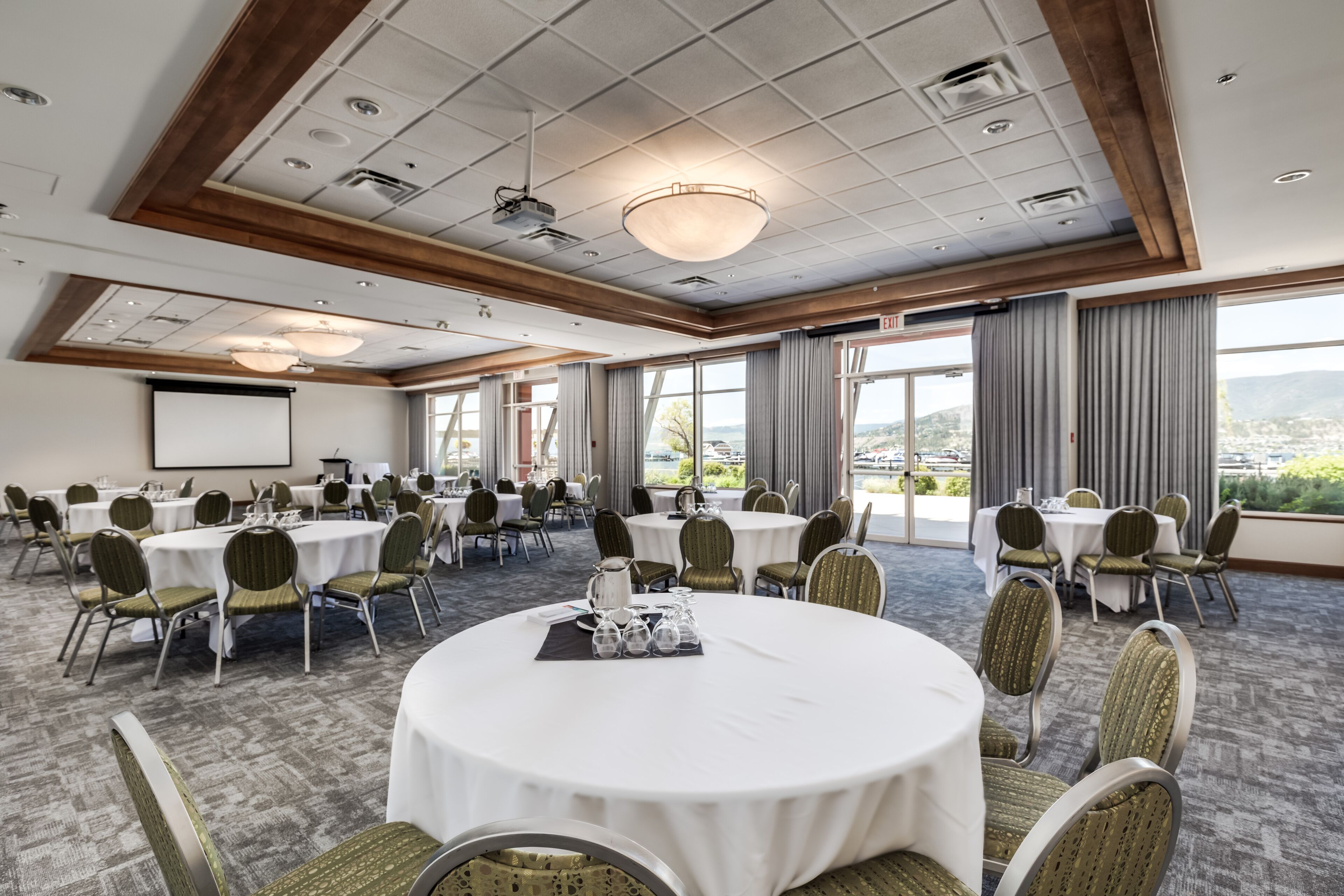 A conference room with round tables, chairs, and a projector screen.