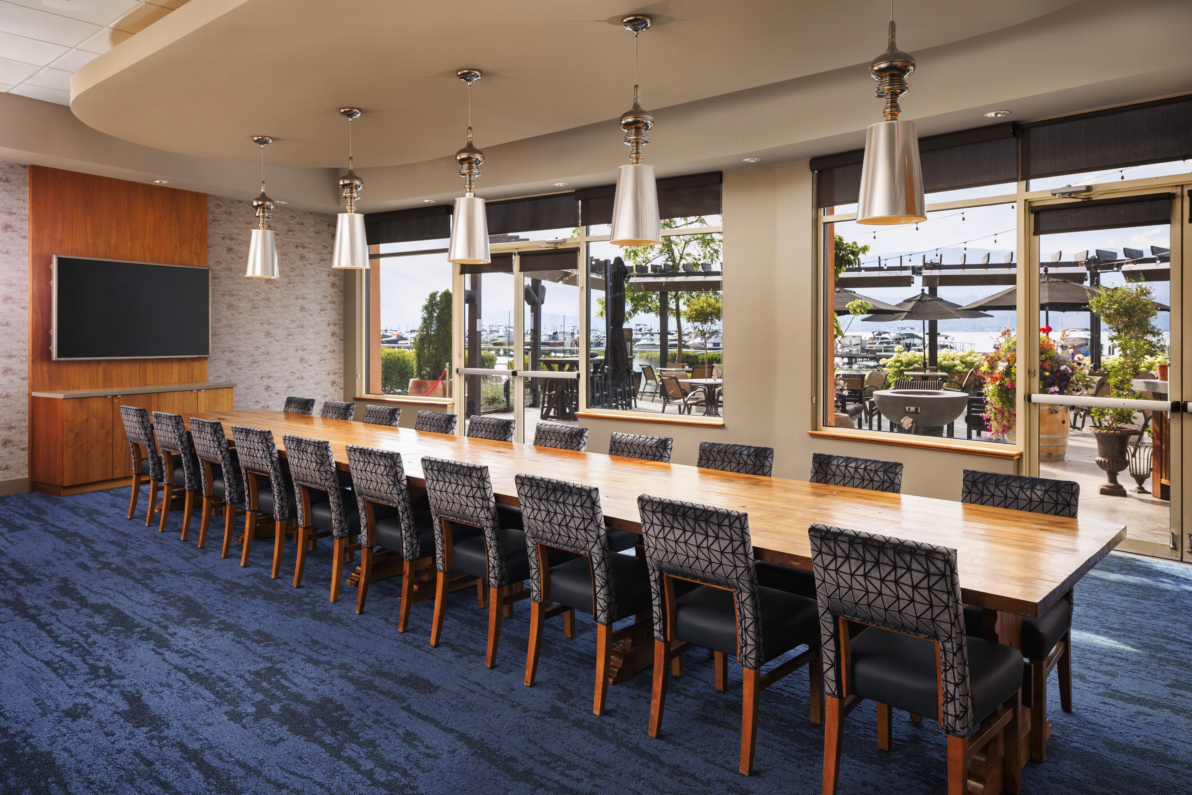 A conference room with a long table, chairs, and pendant lights.