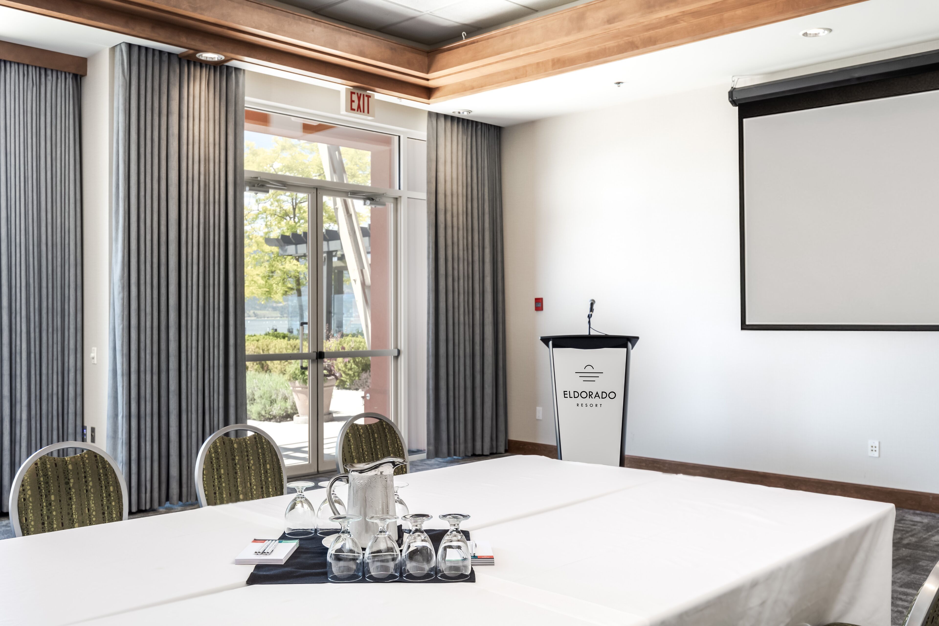 A conference room with a white table, four chairs, a projector screen, and a podium labeled "Eldorado Resort".