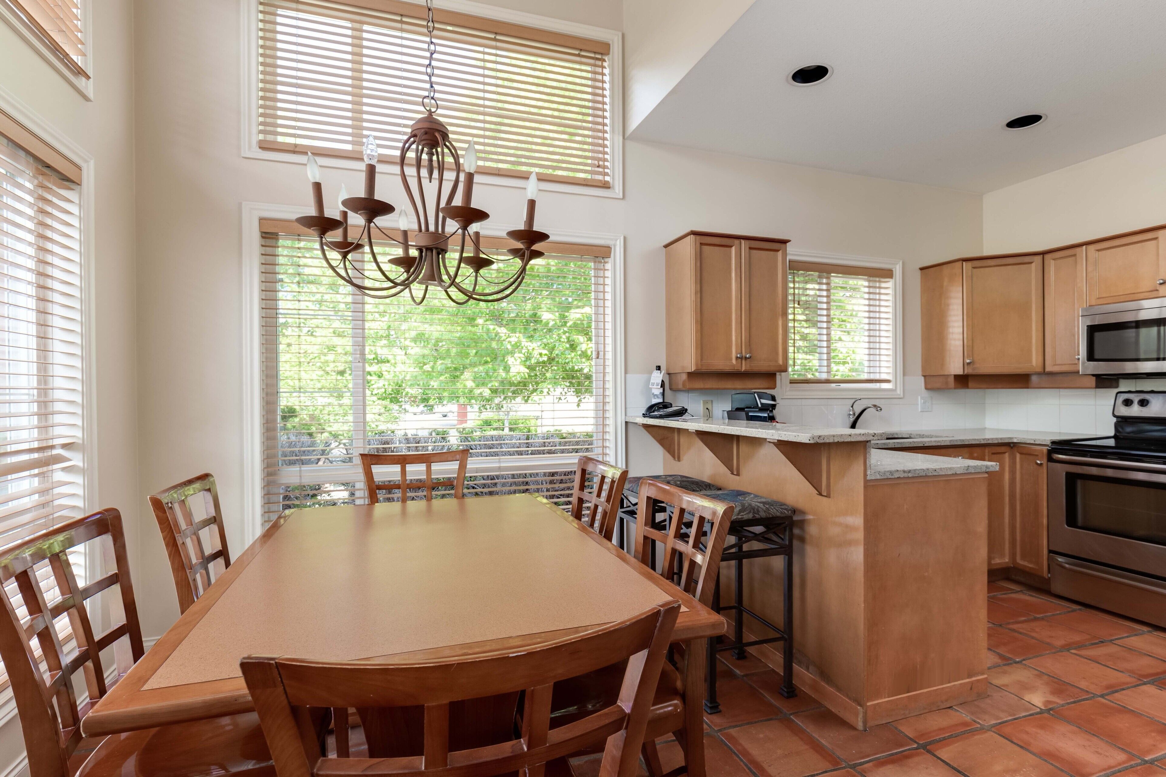 A kitchen with wooden cabinets, a central island, and a dining area with a table and chairs.