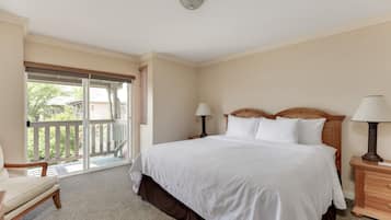 A hotel room with a large bed, two bedside tables with lamps, a chair, and a balcony with a view.