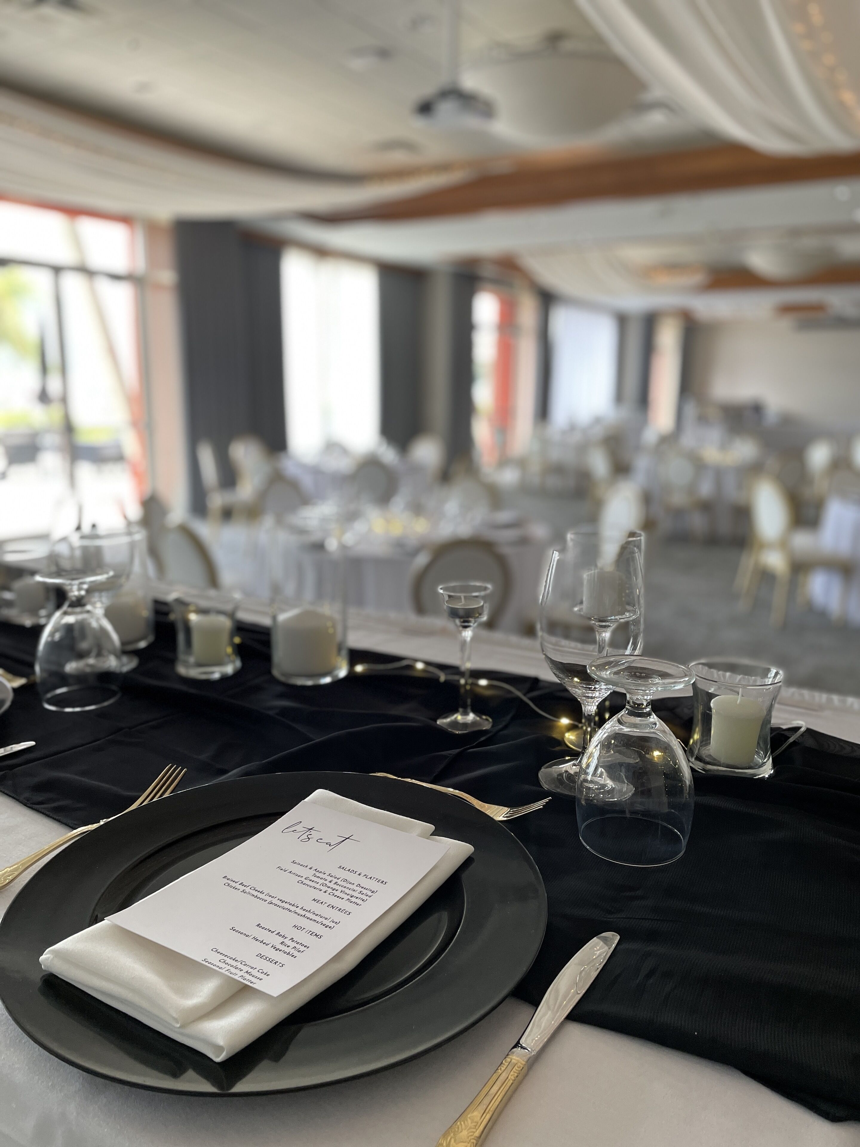 A formal dining setup with a menu, elegant tableware, and candle holders.
