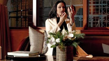 A person sitting at a wooden table with a vase of flowers, a book, and a candle.