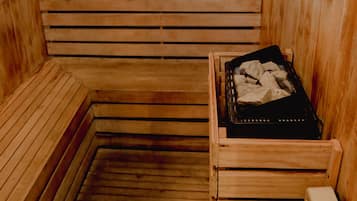 Una sauna con bancos de madera y un banco con una bandeja negra que contiene piedras.