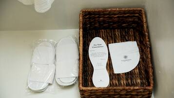 Una cesta de mimbre con una etiqueta blanca y un par de pantuflas blancas.