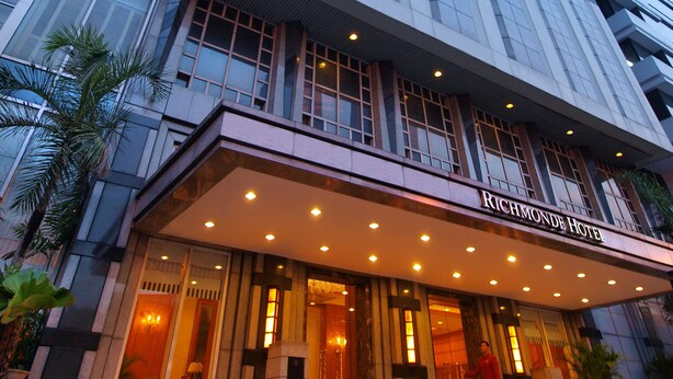 A tall, modern hotel building with a glass facade and a prominent entrance. - Richmonde Hotel Ortigas (Pasig)