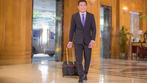 A man in a suit with a briefcase walking in a lobby with polished floors and wooden paneling. - Richmonde Hotel Ortigas (Pasig)