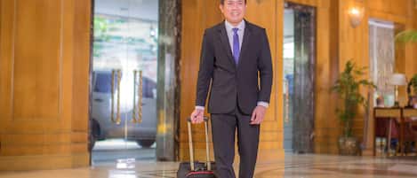 A man in a suit with a briefcase walking in a lobby with polished floors and wooden paneling.