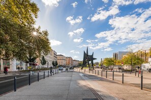 A city square with a large abstract sculpture, a tram line, and buildings in the background. - Hotel Terminus (Grenoble)