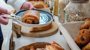 Un bufé con diversas opciones de comida, incluyendo pastelería y tarros de granola.