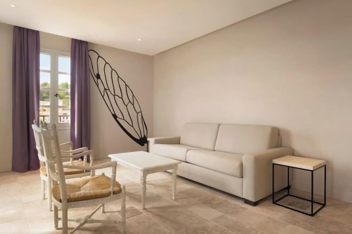 A modern living room with a white sofa, a white coffee table, a white chair, and a black side table.