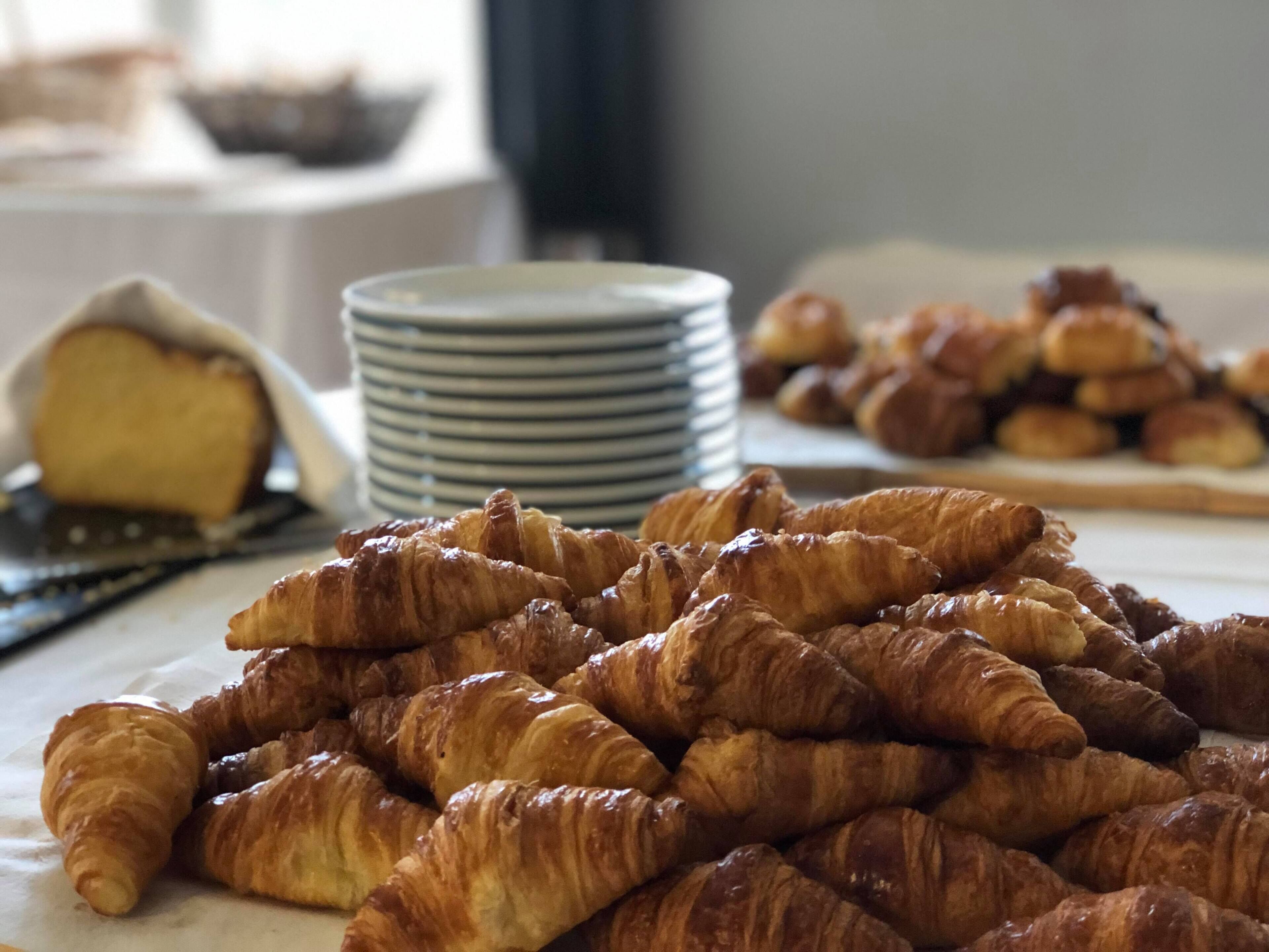 A table with an assortment of pastries, including croissants and a cake.