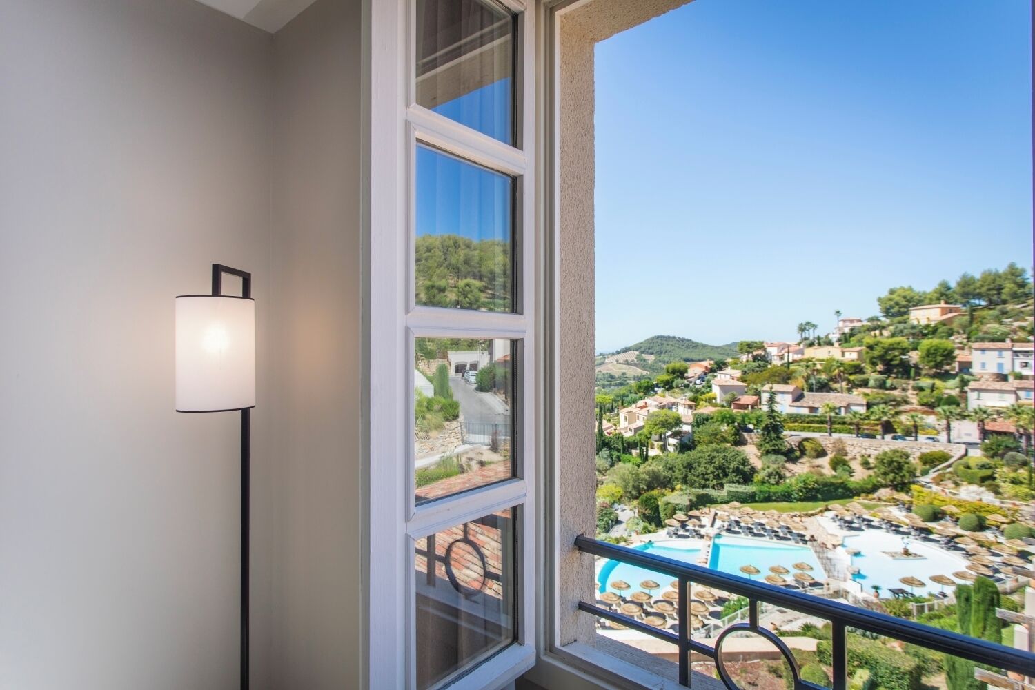 A balcony with a view of a pool and a hillside town.