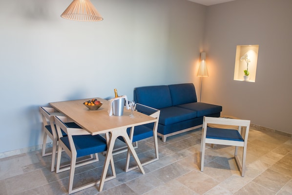 A modern living room with a wooden dining table, blue sofa, and matching chairs.