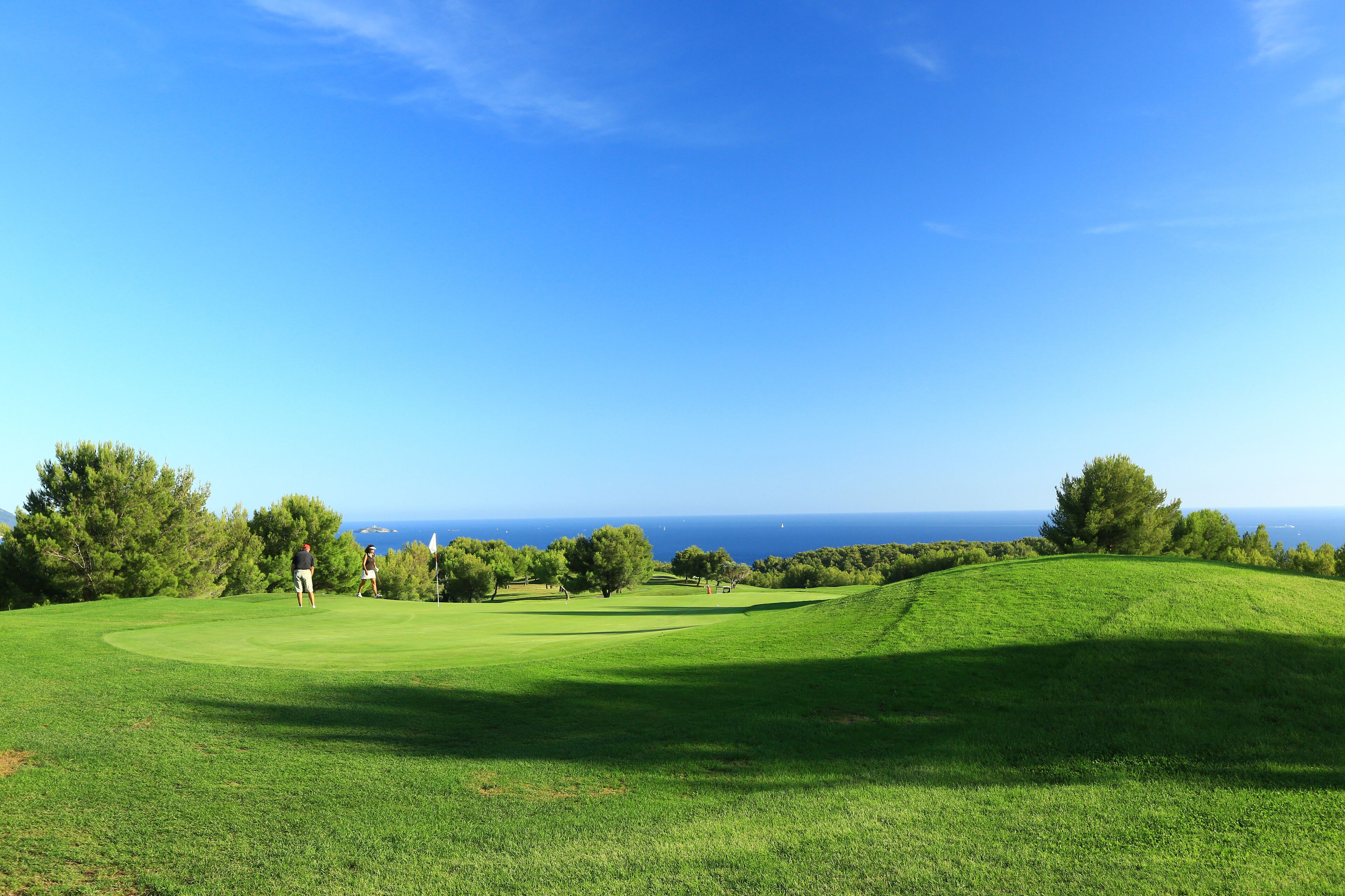 A golf course with a clear view of the ocean in the background.
